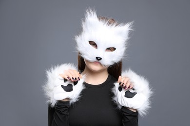 Photo of Quadrobics. Girl wearing cat mask and gloves on grey background