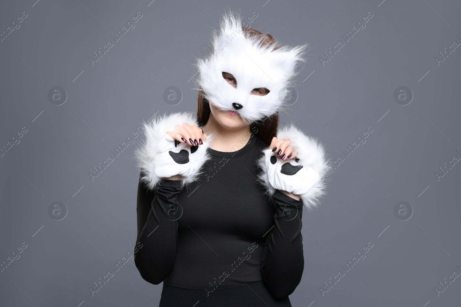 Photo of Quadrobics. Girl wearing cat mask and gloves on grey background