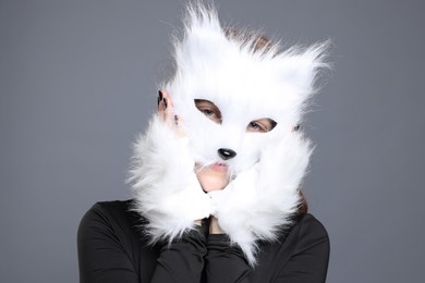 Photo of Quadrobics. Girl wearing cat mask and gloves on grey background