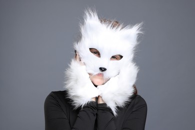 Photo of Quadrobics. Girl wearing cat mask and gloves on grey background