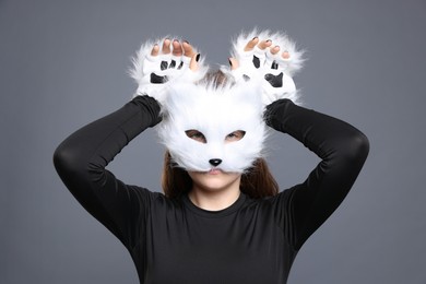 Photo of Quadrobics. Girl wearing cat mask and gloves on grey background