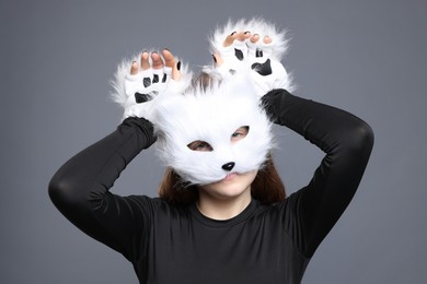 Photo of Quadrobics. Girl wearing cat mask and gloves on grey background