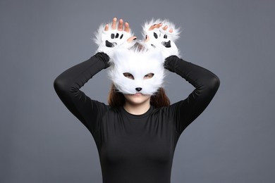 Photo of Quadrobics. Girl wearing cat mask and gloves on grey background