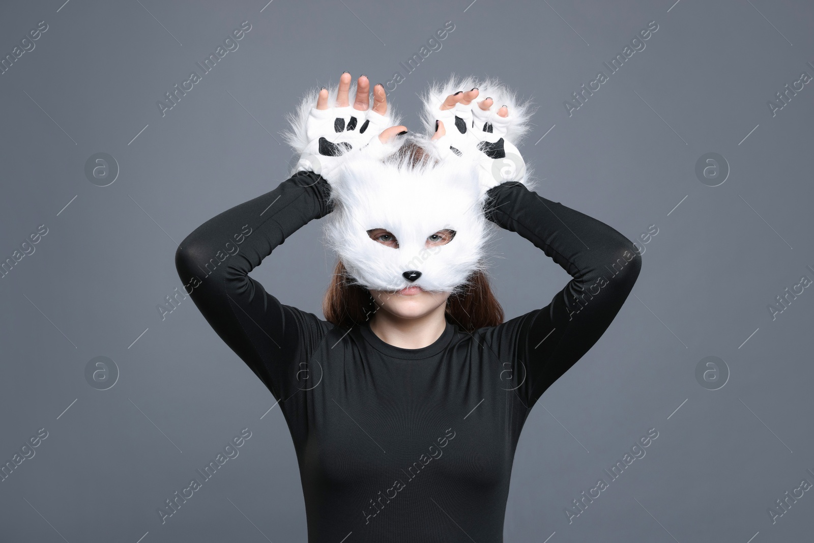 Photo of Quadrobics. Girl wearing cat mask and gloves on grey background