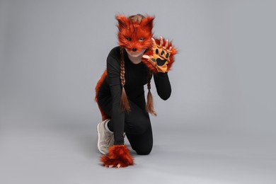 Photo of Quadrobics. Girl wearing fox mask and gloves on grey background