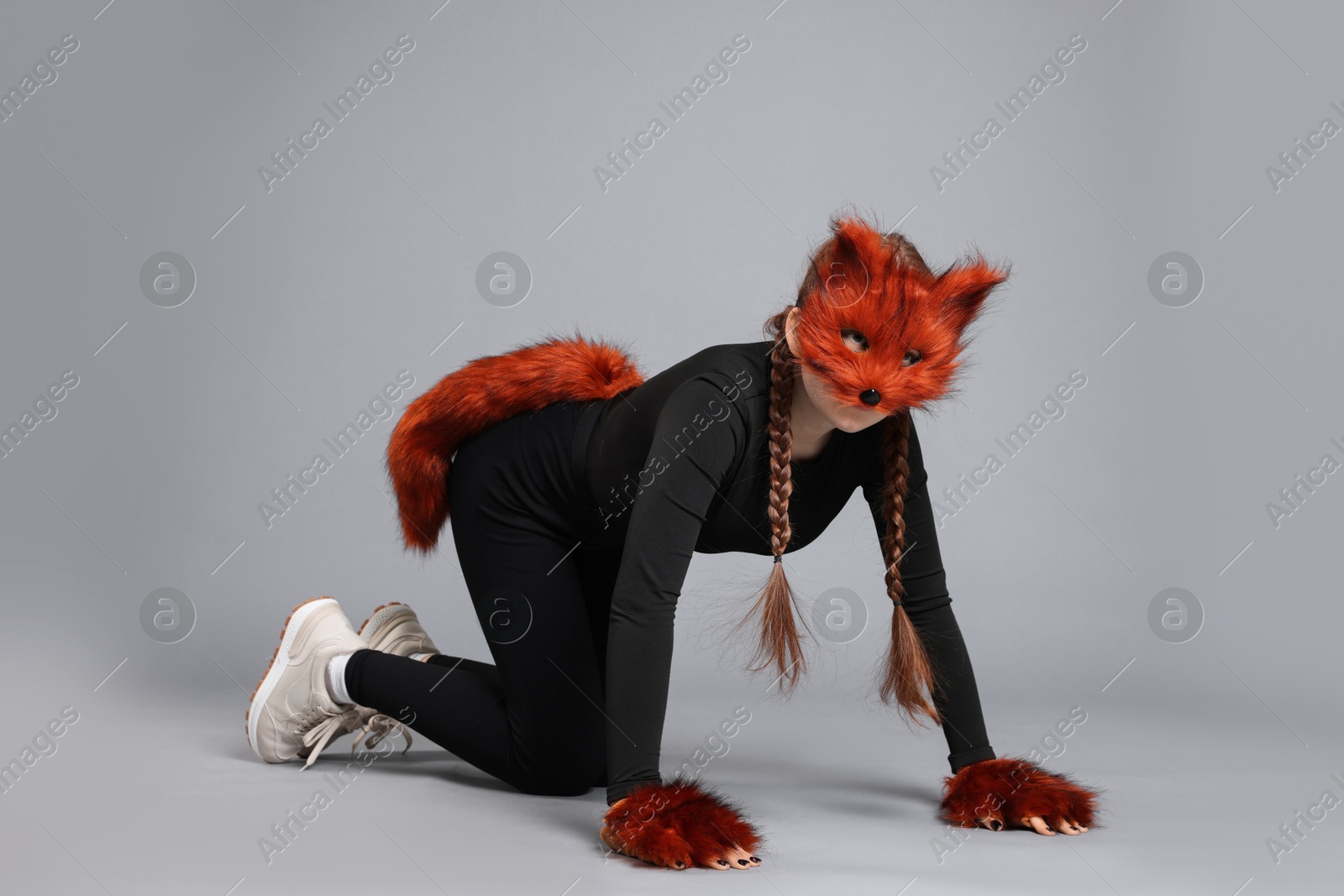 Photo of Quadrobics. Girl wearing fox mask, gloves and tail on grey background