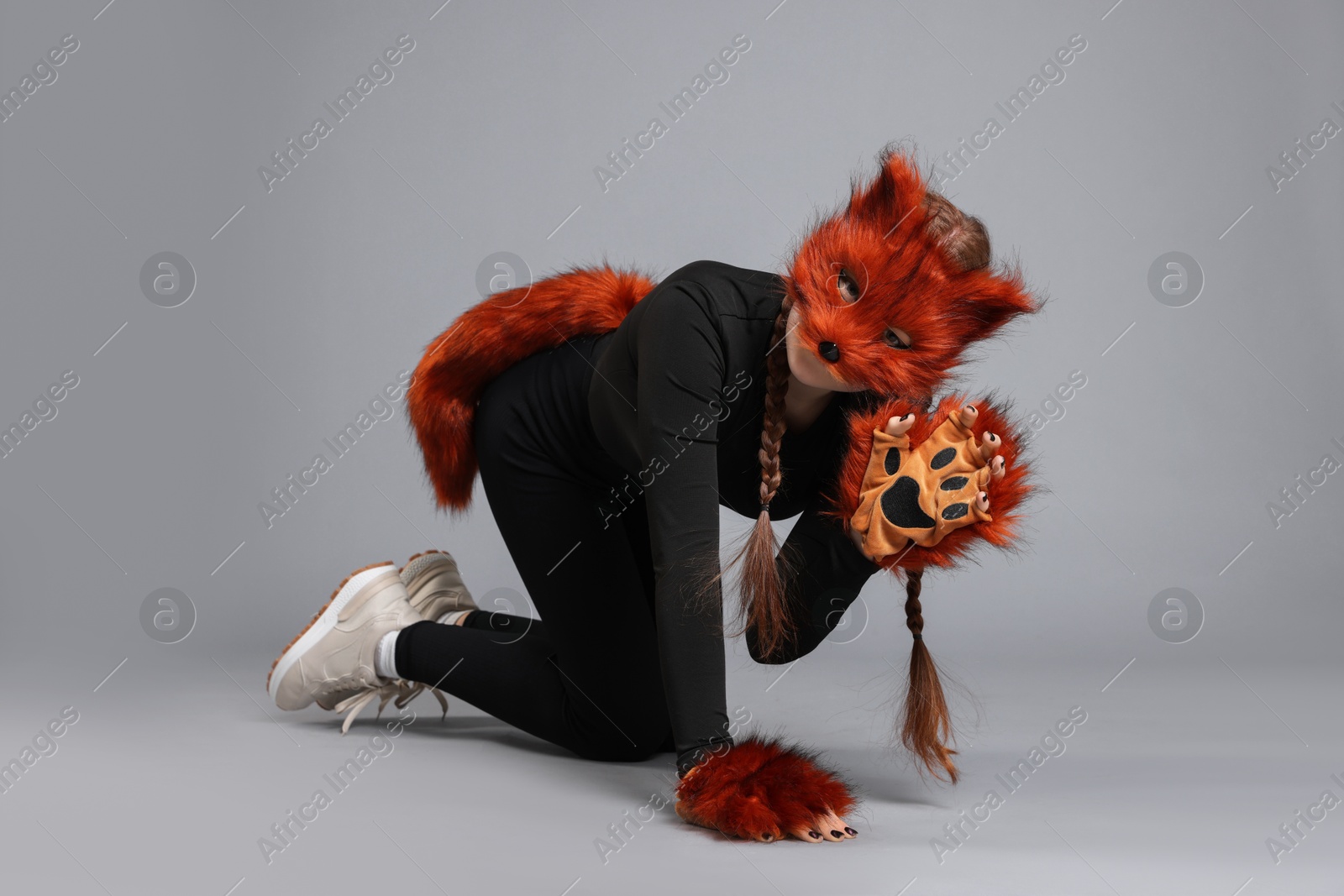 Photo of Quadrobics. Girl wearing fox mask, gloves and tail on grey background