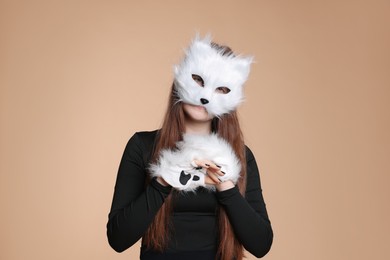 Photo of Quadrobics. Girl wearing cat mask and gloves on beige background