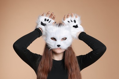 Photo of Quadrobics. Girl wearing cat mask and gloves on beige background