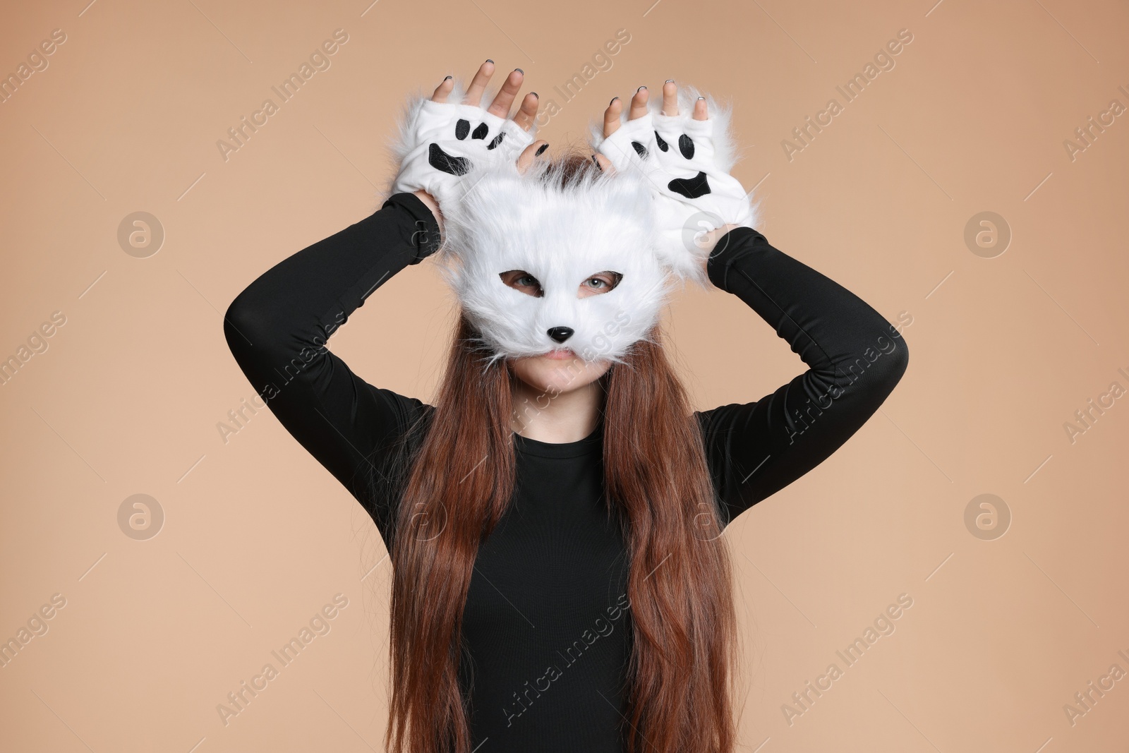 Photo of Quadrobics. Girl wearing cat mask and gloves on beige background