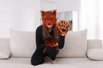 Photo of Quadrobics. Girl wearing fox mask and gloves on sofa at home