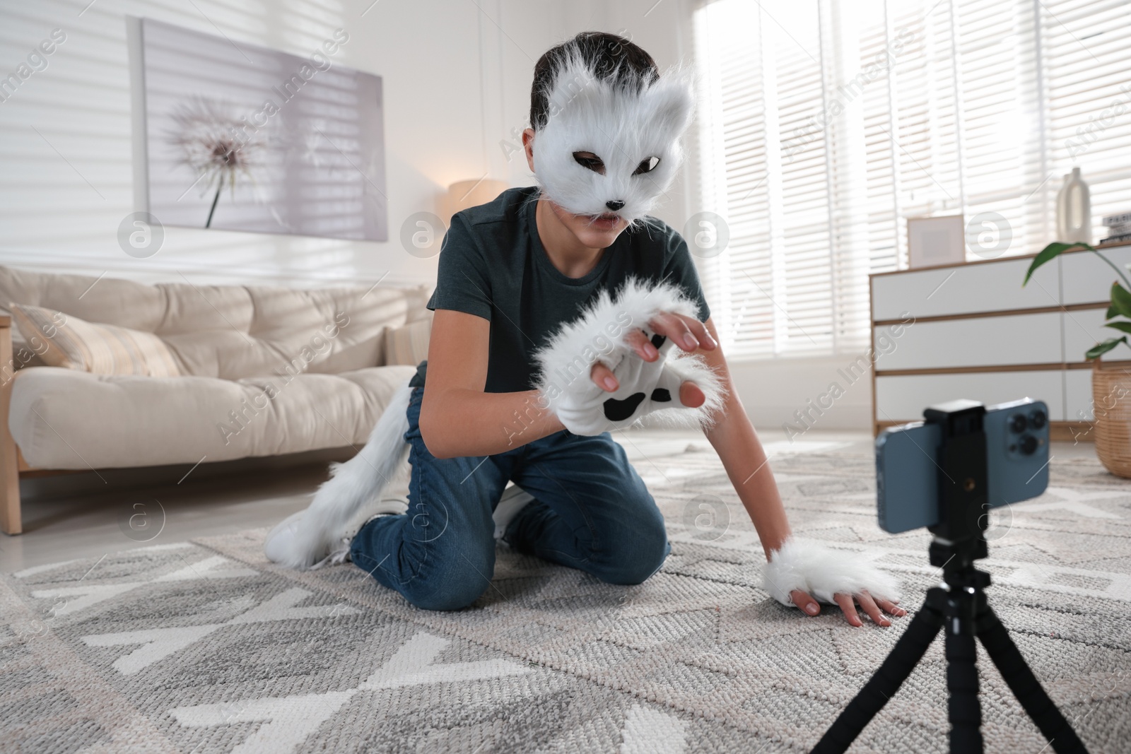 Photo of Quadrobics. Boy in cat mask, gloves and tail recording video at home