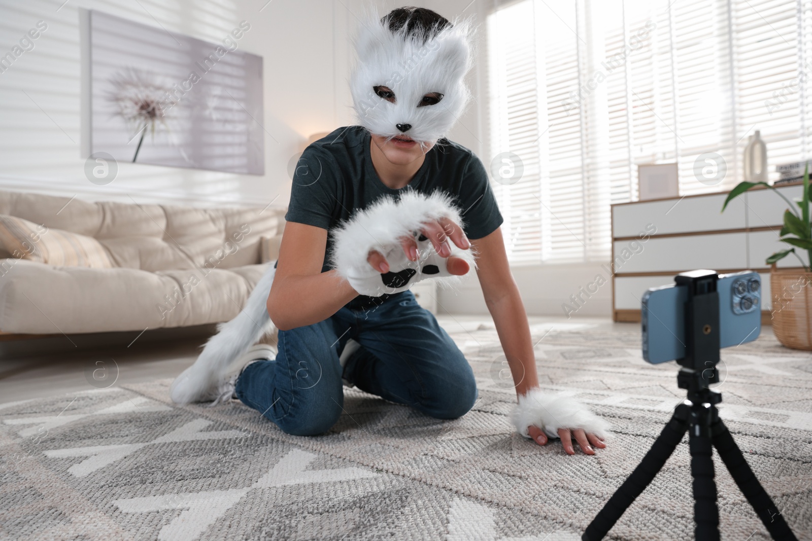 Photo of Quadrobics. Boy in cat mask, gloves and tail recording video at home