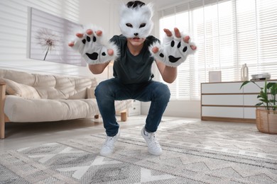 Photo of Quadrobics. Boy wearing cat mask and gloves at home