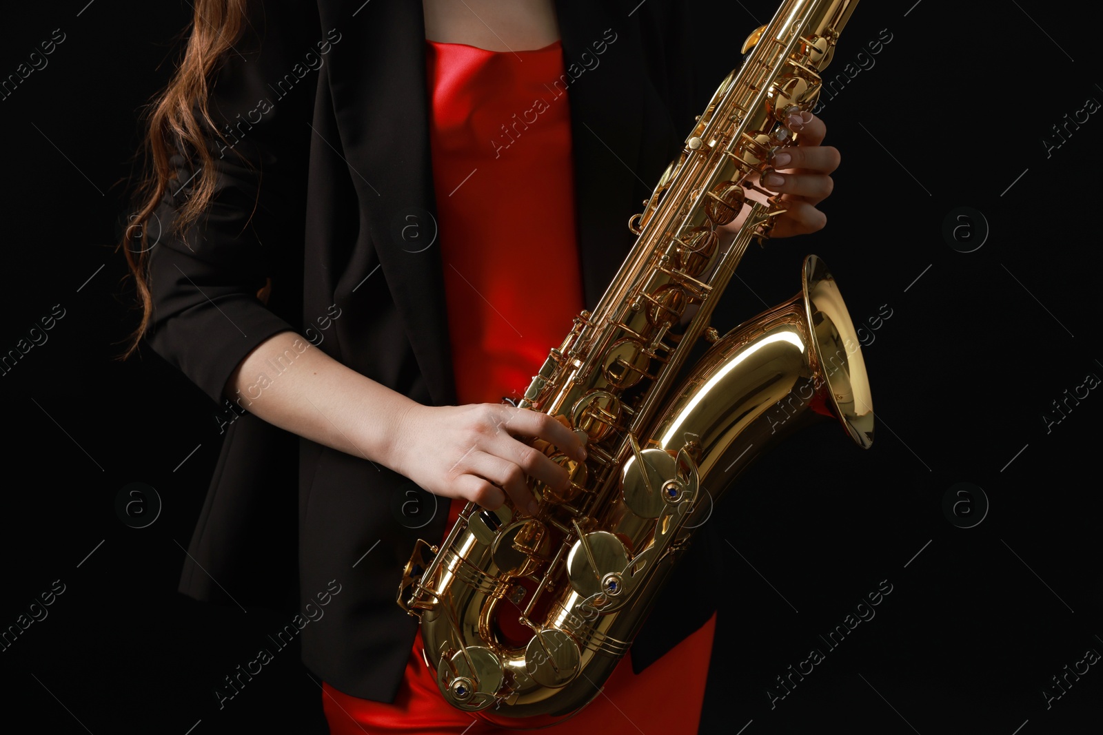 Photo of Professional musician with saxophone on black background, closeup