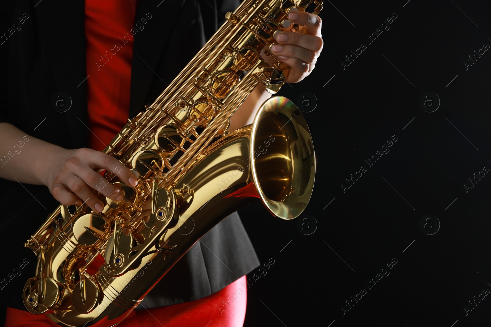 Photo of Professional musician with saxophone on black background, closeup