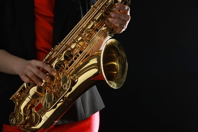 Photo of Professional musician with saxophone on black background, closeup