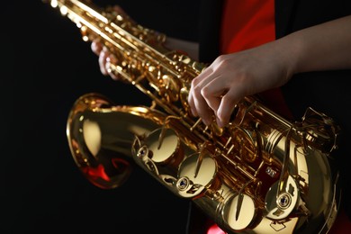 Photo of Professional musician with saxophone on black background, closeup