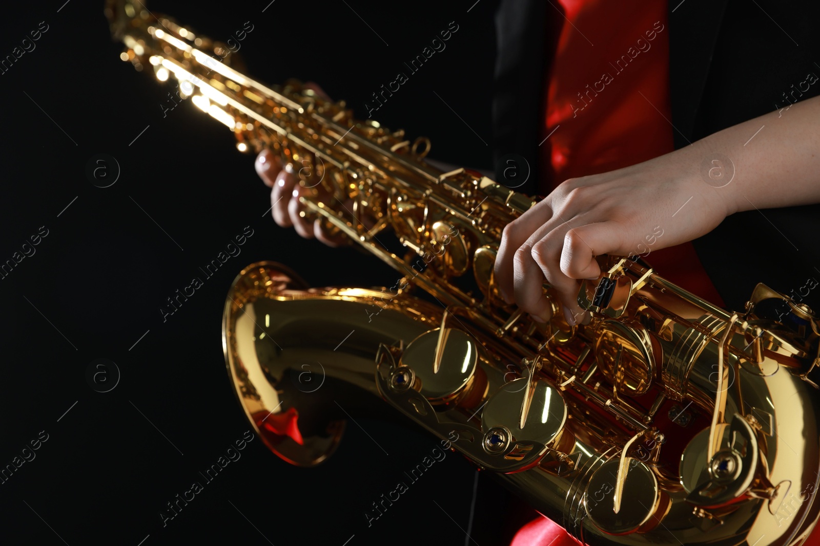 Photo of Professional musician with saxophone on black background, closeup