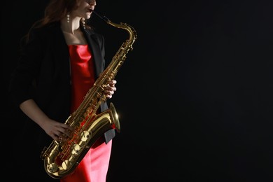 Photo of Professional musician playing saxophone on black background, closeup. Space for text