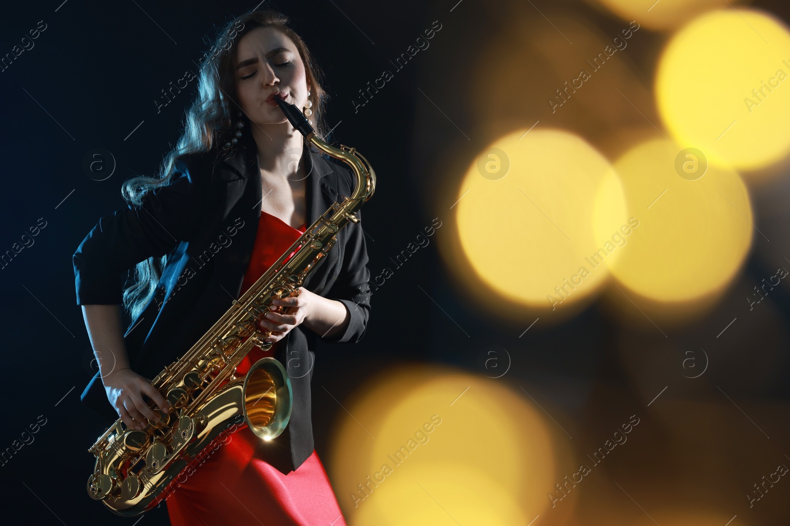 Photo of Professional musician playing saxophone on black background with blurred lights. Bokeh effect