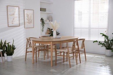 Photo of Stylish wooden table with chairs and decor indoors. Interior design