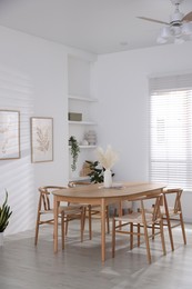 Photo of Stylish wooden table with chairs and decor indoors. Interior design