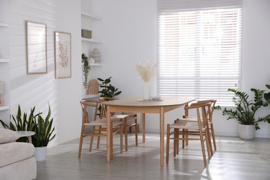 Photo of Stylish wooden table with chairs and decor indoors. Interior design