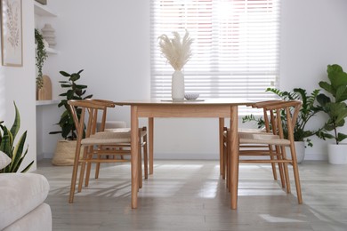 Photo of Stylish wooden table with chairs and decor indoors. Interior design