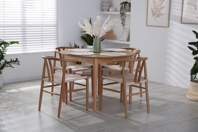 Photo of Stylish wooden table with chairs and decor indoors. Interior design