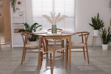 Photo of Stylish wooden table with chairs and decor indoors. Interior design