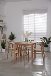 Photo of Stylish wooden table with chairs and decor indoors. Interior design