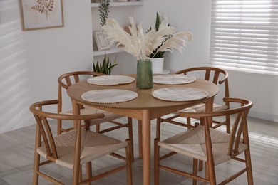 Photo of Stylish wooden table with chairs and decor indoors. Interior design