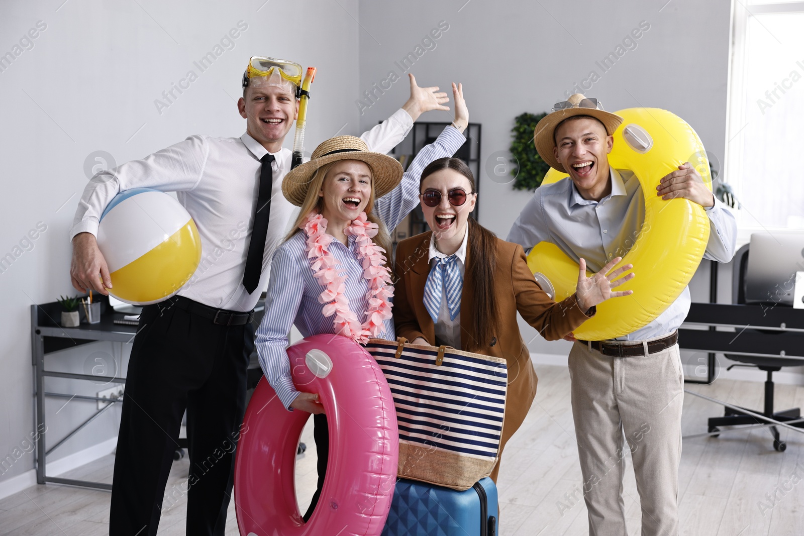 Photo of Colleagues with different beach accessories having fun in office