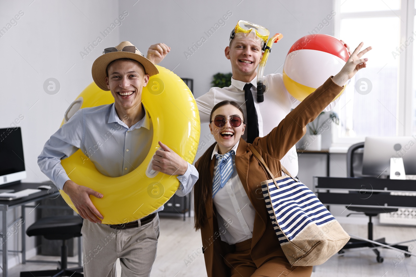 Photo of Colleagues with different beach accessories having fun in office