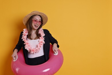 Photo of Businesswoman with inflatable ring, straw hat, flower wreath and sunglasses on orange background, space for text