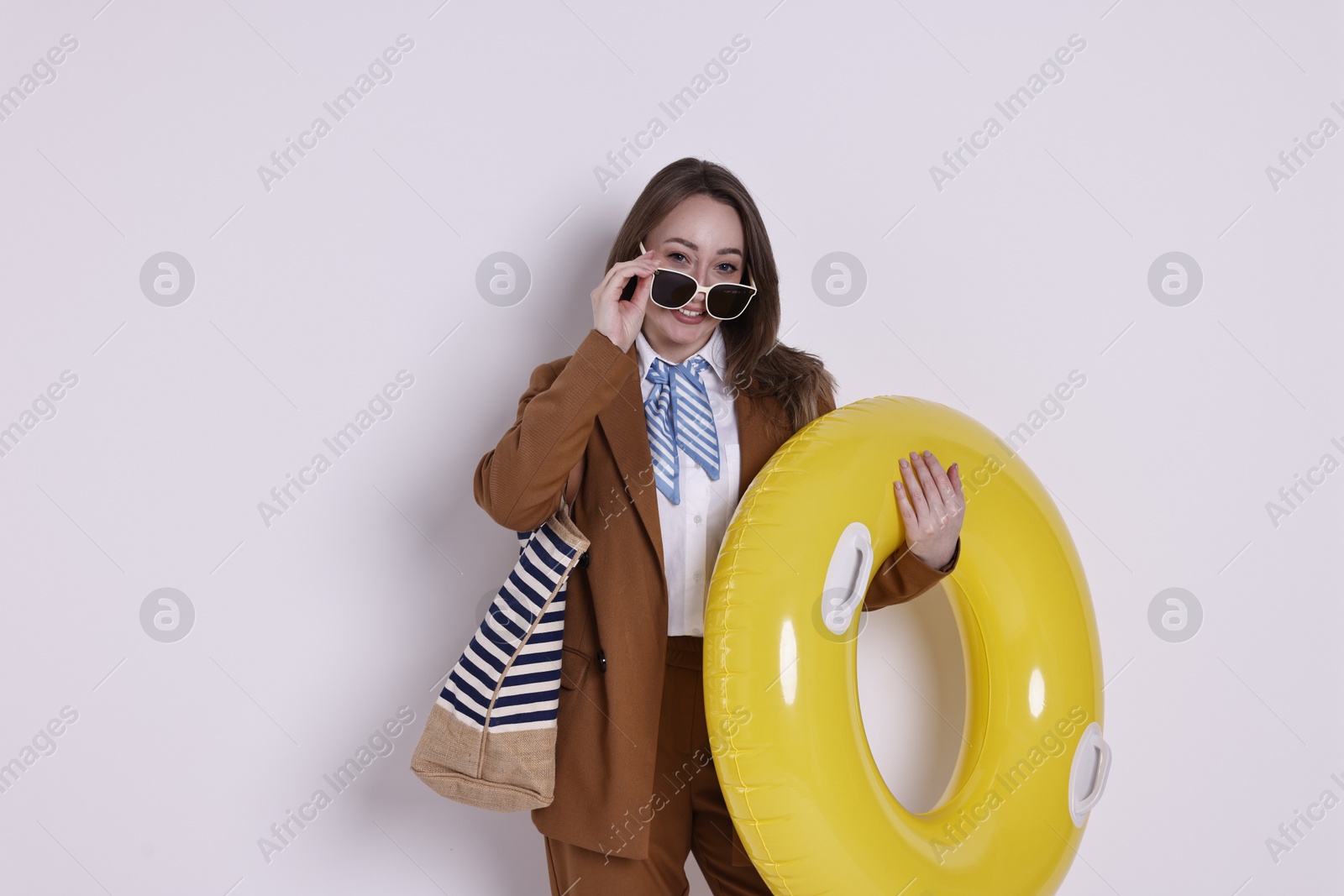 Photo of Businesswoman with inflatable ring, bag and sunglasses on white background