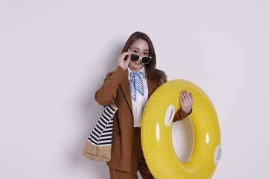 Photo of Businesswoman with inflatable ring, bag and sunglasses on white background