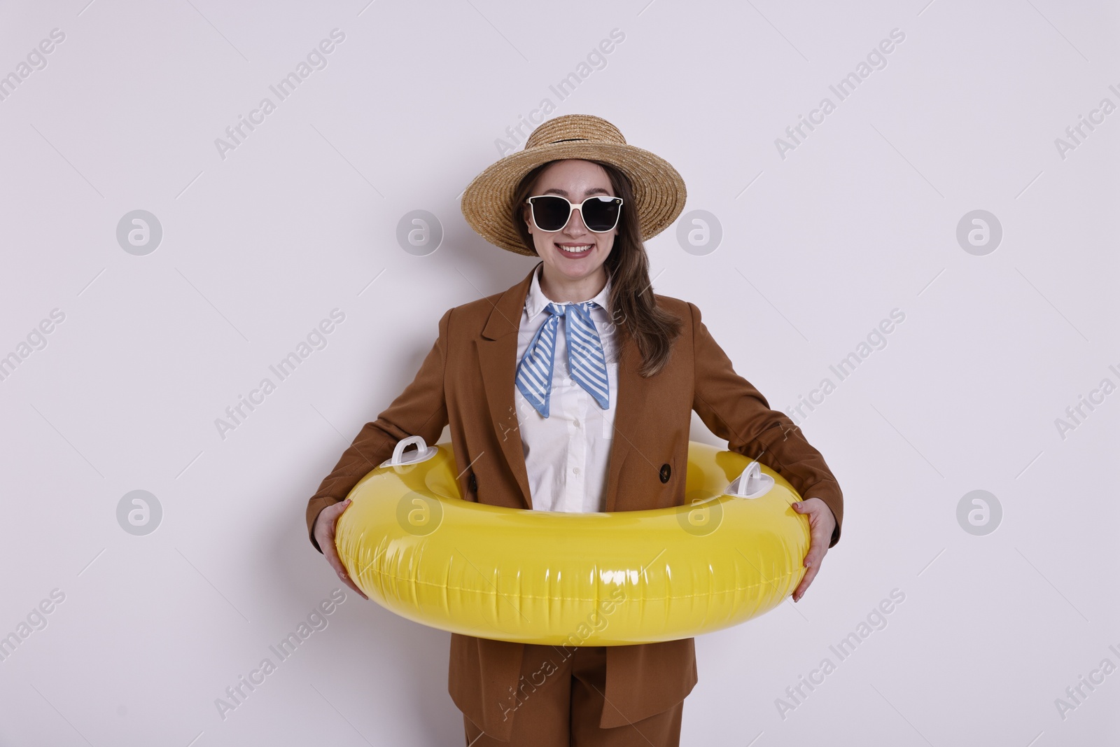 Photo of Businesswoman with inflatable ring, straw hat and sunglasses on white background