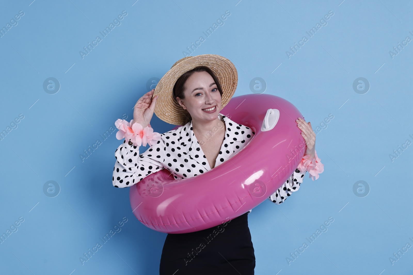 Photo of Businesswoman with inflatable ring, straw hat and flower bracelets on light blue background