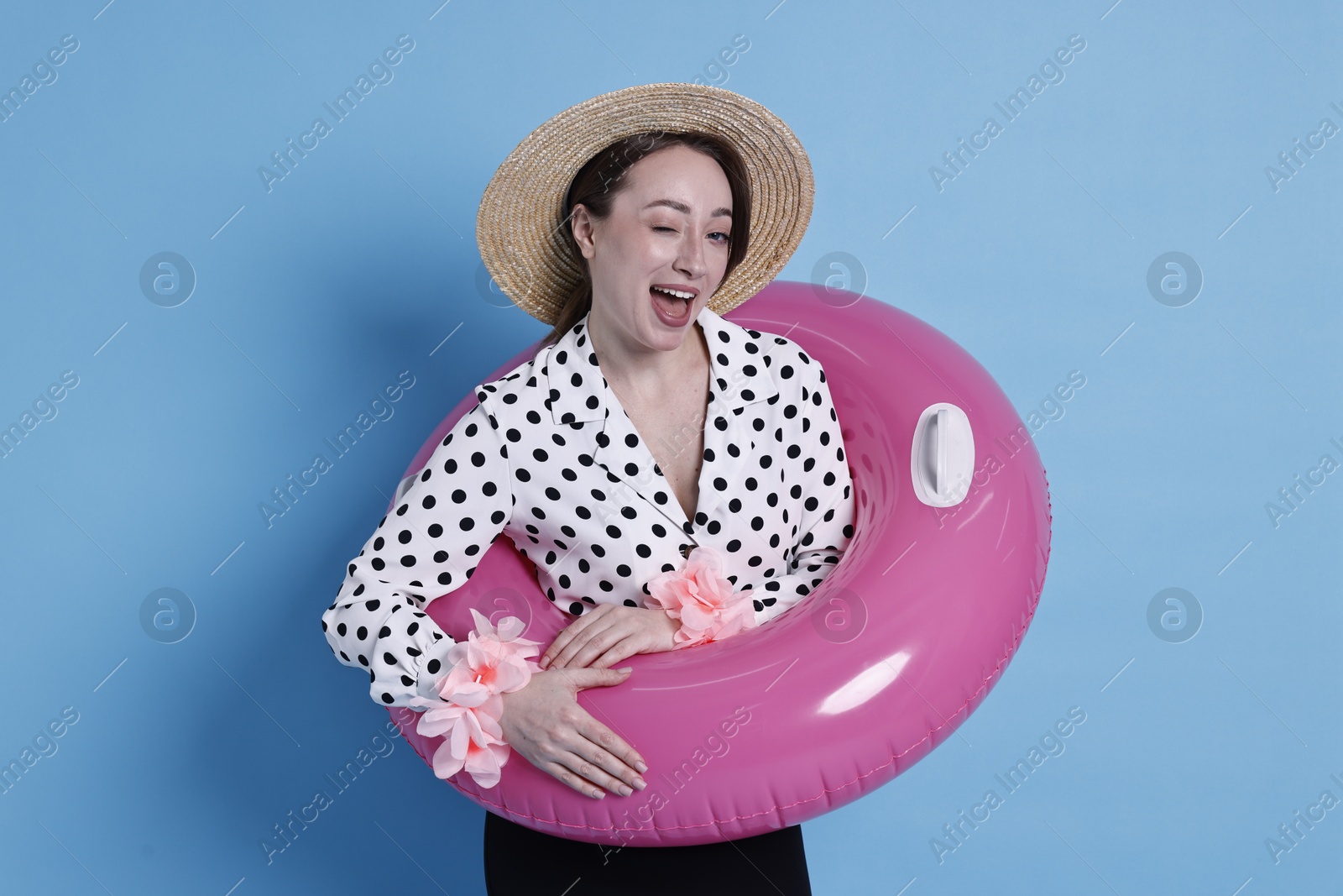 Photo of Businesswoman with inflatable ring, straw hat and flower bracelets on light blue background