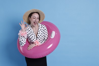 Photo of Businesswoman with inflatable ring, straw hat and flower bracelets showing ok gesture on light blue background, space for text