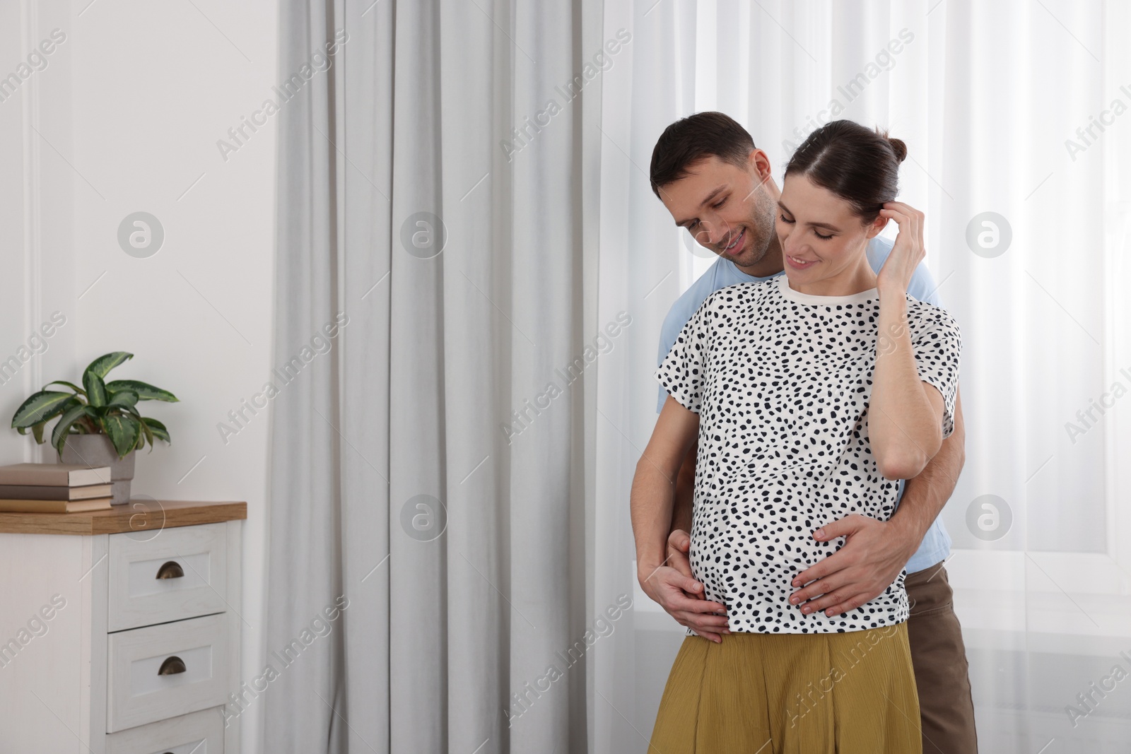 Photo of Pregnant woman and her husband at home. Space for text