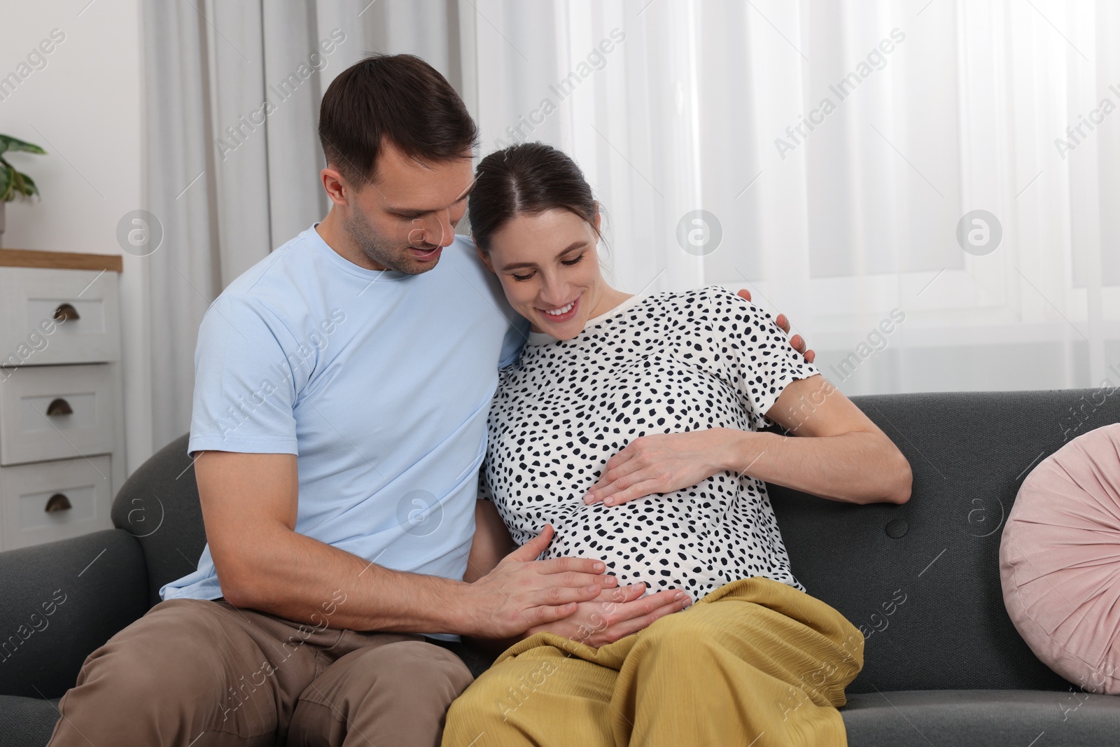 Photo of Pregnant woman and her husband on sofa at home