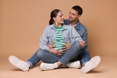 Photo of Pregnant woman and her husband on beige background