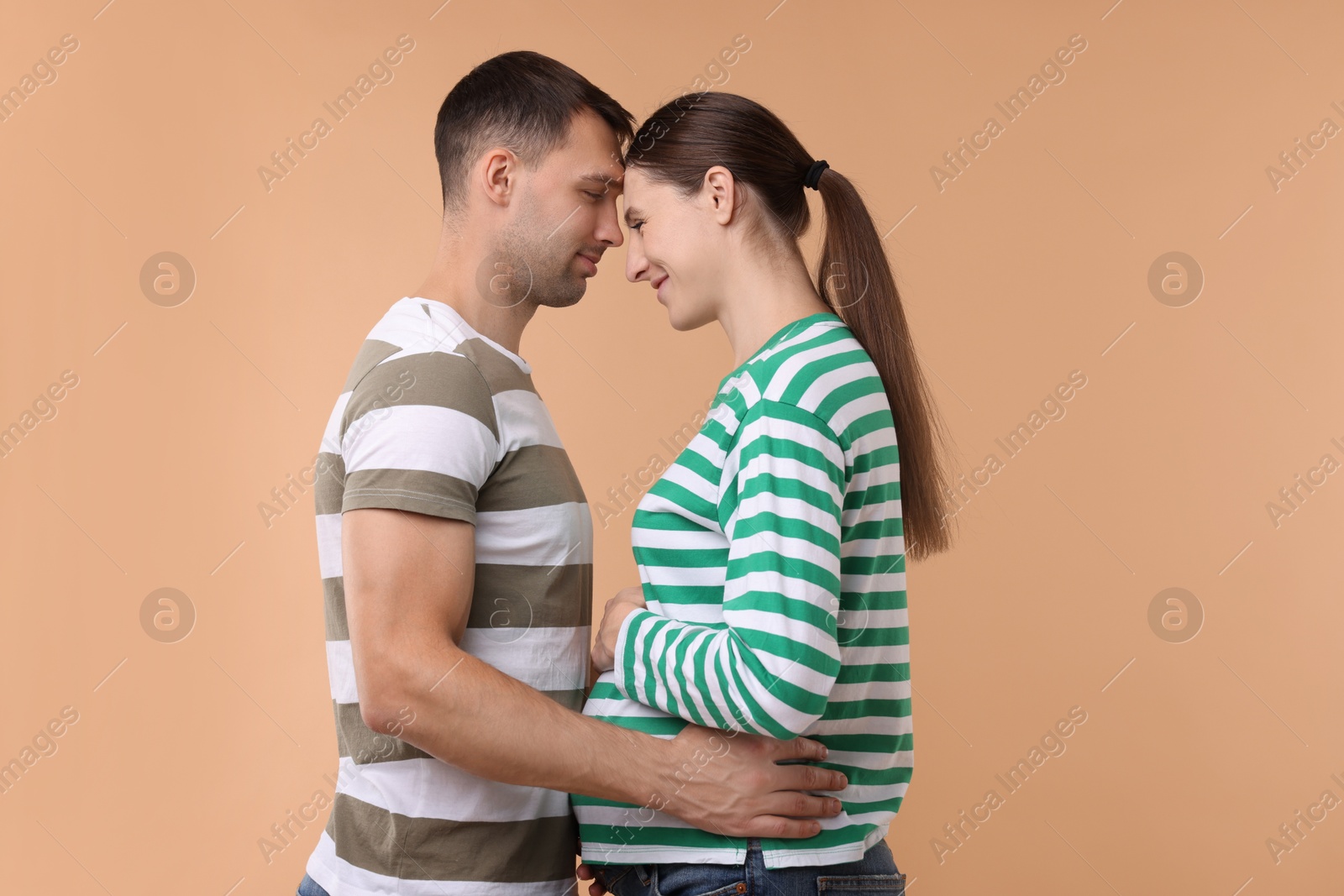 Photo of Pregnant woman and her husband on beige background