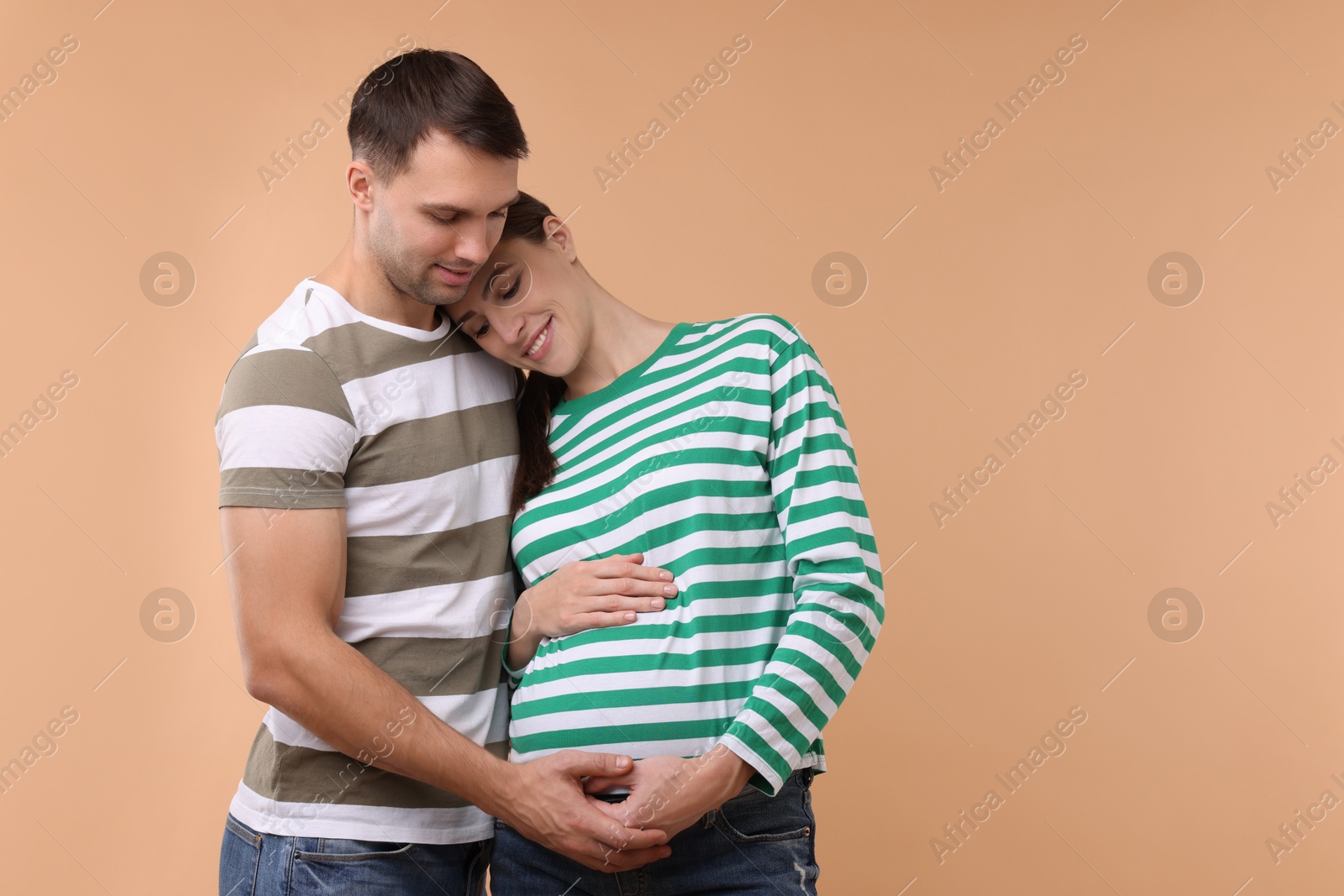 Photo of Pregnant woman and her husband on beige background. Space for text