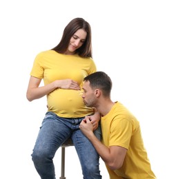 Photo of Man kissing his pregnant wife's belly on white background