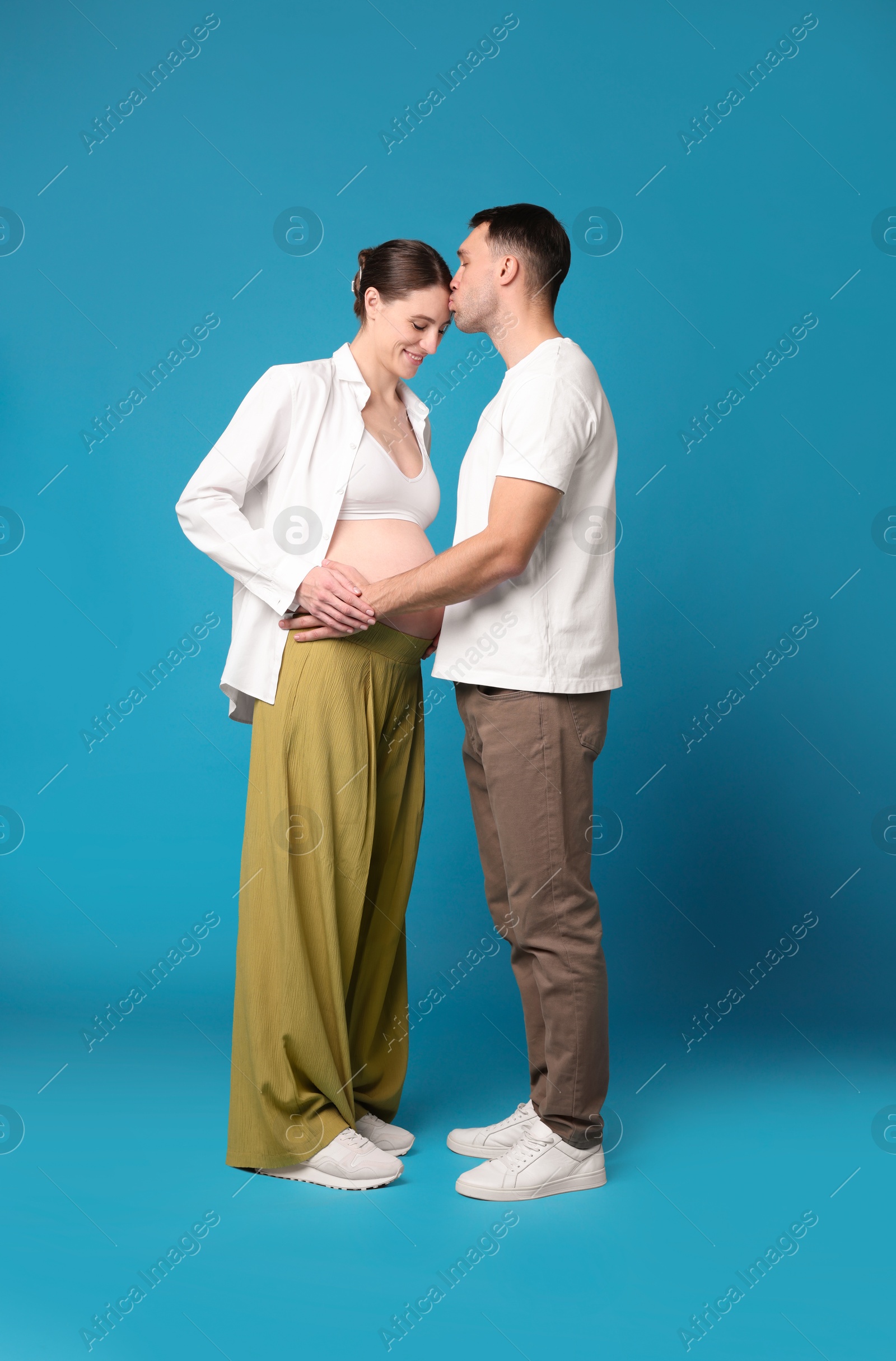 Photo of Pregnant woman and her husband on blue background