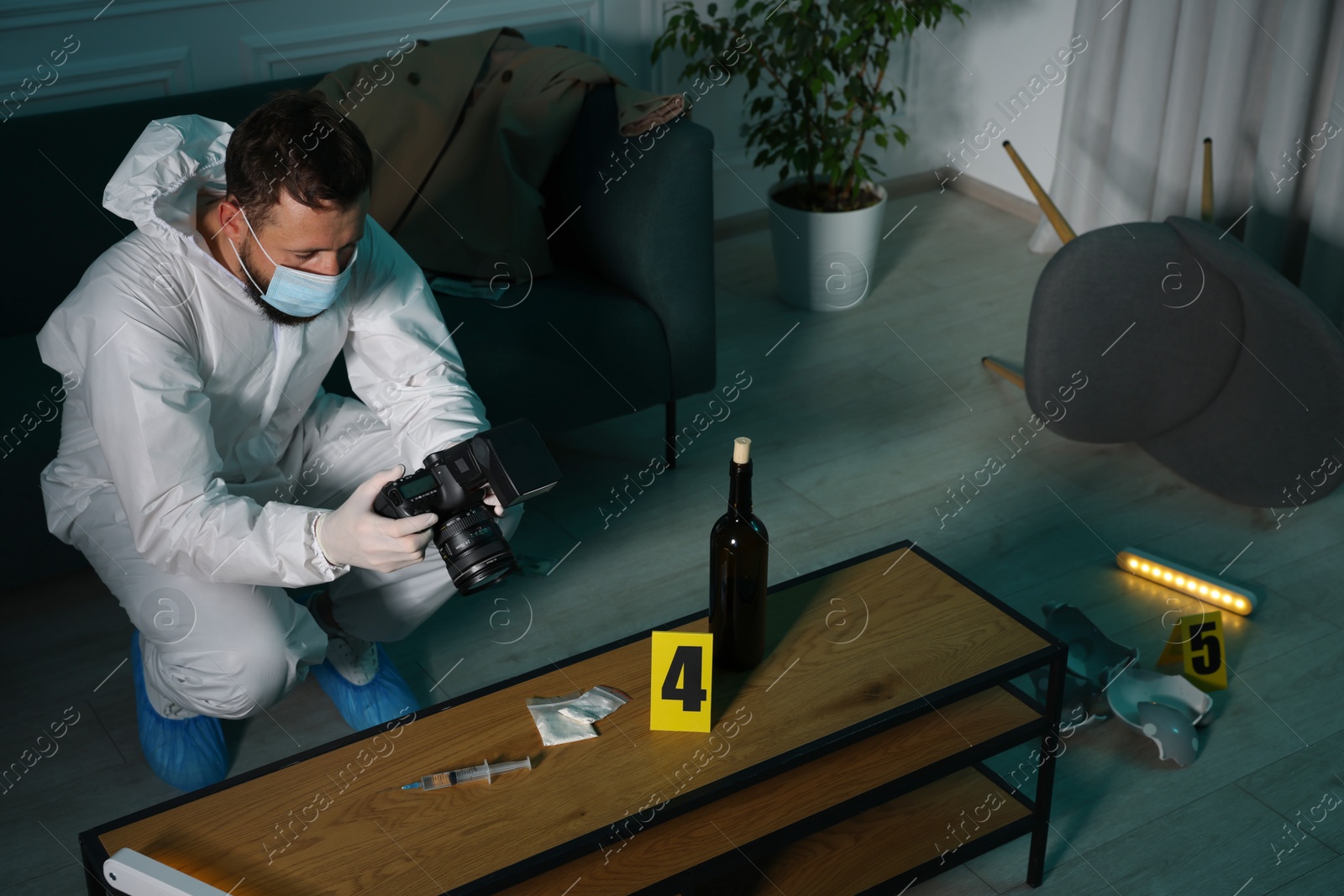 Photo of Forensic expert with camera taking photo of evidences at crime scene indoors